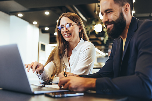 Man and woman smiling while looking at a laptop